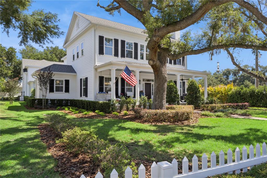 A white two-story house with a front porch, black shutters, and a picket fence — 811 CIVITAS WAY, WINTER GARDEN, FL