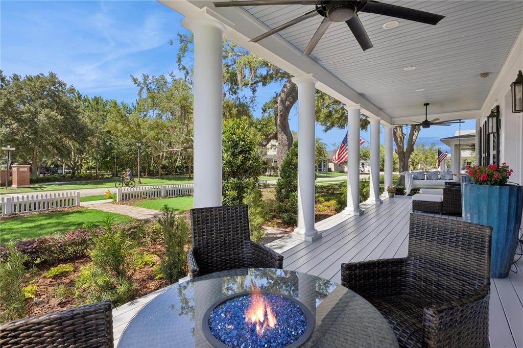 A covered porch features a glass-topped fire pit table, wicker chairs, and white columns — 811 CIVITAS WAY, WINTER GARDEN, FL
