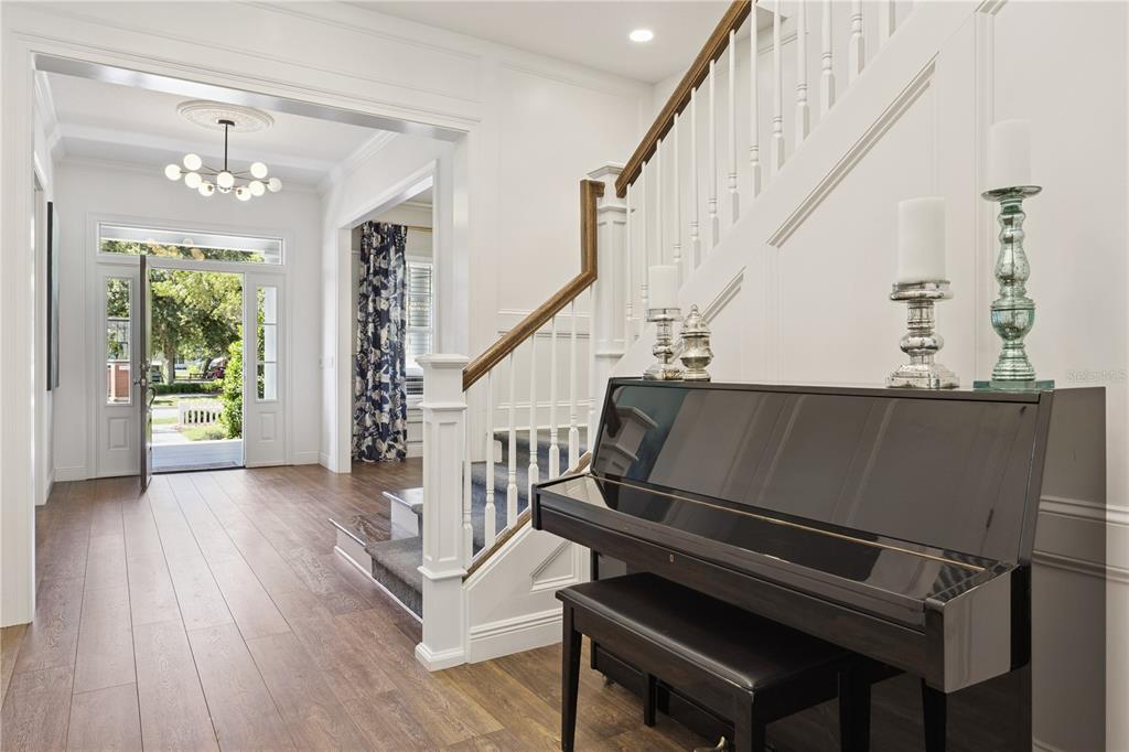 A foyer with a piano, staircase, and an open front door leading to a porch — 811 CIVITAS WAY, WINTER GARDEN, FL