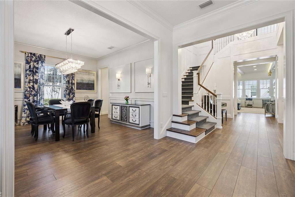 A dining room with a crystal chandelier and a staircase with dark wood treads — 811 CIVITAS WAY, WINTER GARDEN, FL