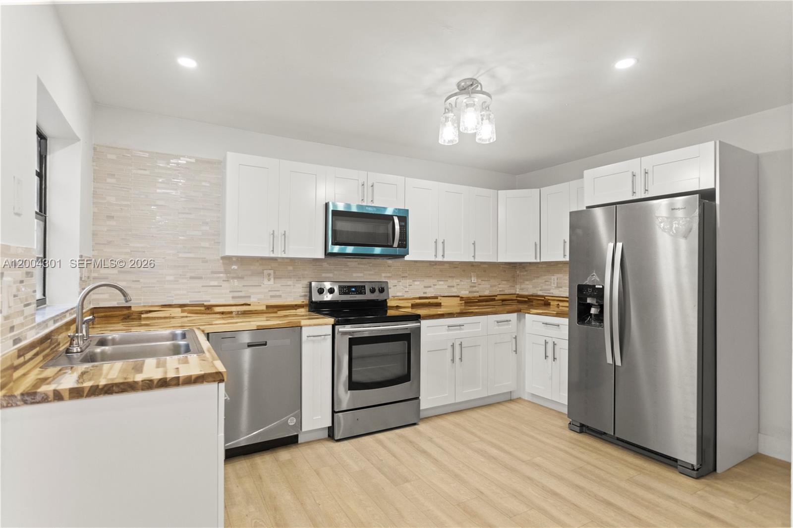 A kitchen features white cabinets, stainless steel appliances, and wood-look countertops — 6745 NW 169th St # G, Hialeah FL 33015, HIALEAH, FL