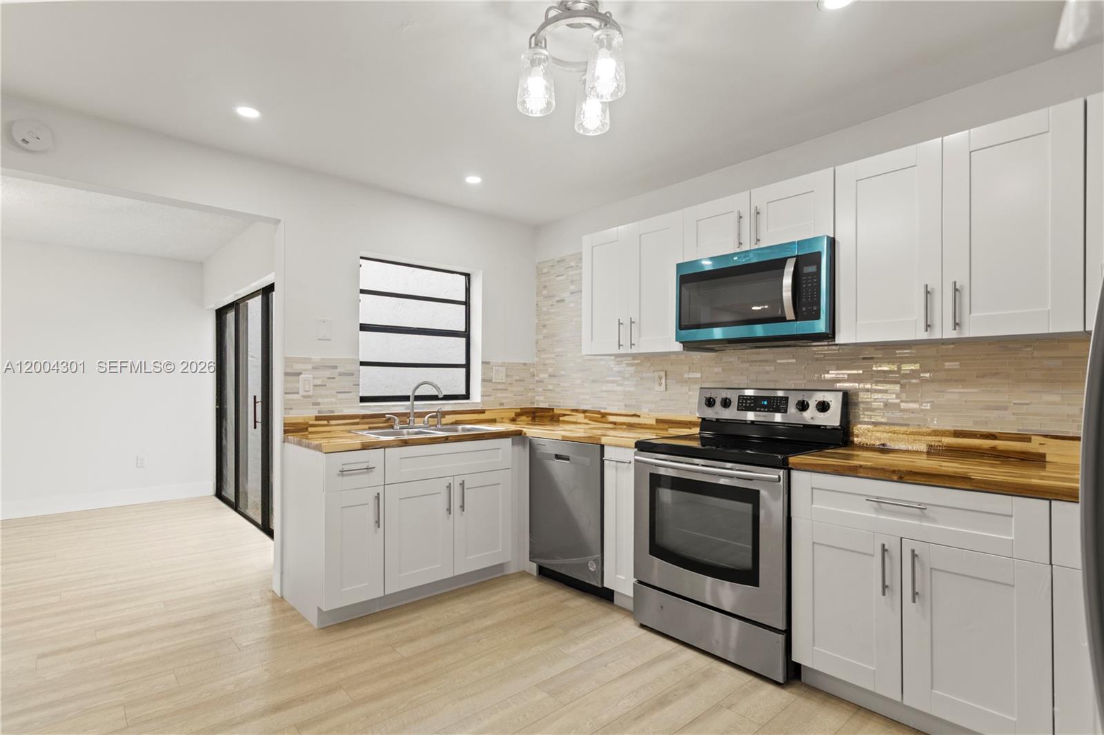 A kitchen features white cabinets, wood countertops, stainless steel appliances, and a tiled backsplash — 6745 NW 169th St # G, Hialeah FL 33015, HIALEAH, FL