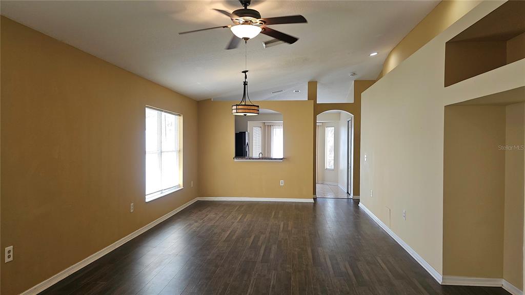 An empty living room features dark wood-look flooring, tan walls, and a ceiling fan — 12629 EVINGTON POINT DRIVE, RIVERVIEW, FL