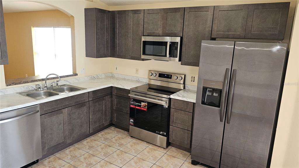 A kitchen features dark wood cabinets, stainless steel appliances, and white marble-patterned countertops — 12629 EVINGTON POINT DRIVE, RIVERVIEW, FL