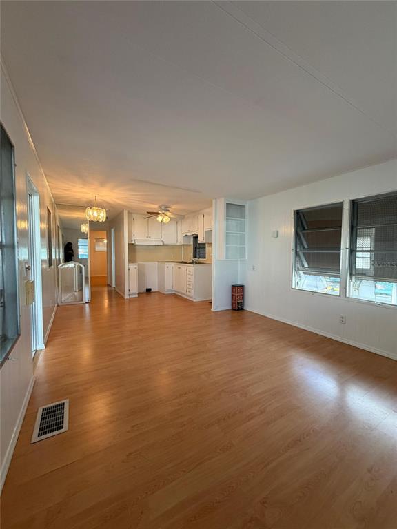 An open-concept living area with light wood flooring leads into a kitchen with white cabinets — 2514 17TH STREET LANE W, BRADENTON, FL