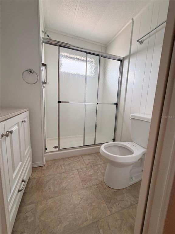 A bathroom features a walk-in shower with sliding glass doors, a toilet, and white cabinetry — 2514 17TH STREET LANE W, BRADENTON, FL