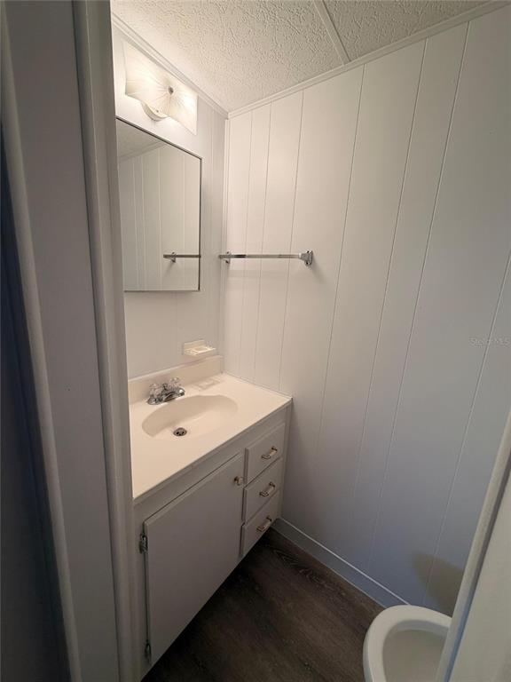 A small bathroom features a white vanity, a wall-mounted mirror, and white vertical paneling — 2514 17TH STREET LANE W, BRADENTON, FL