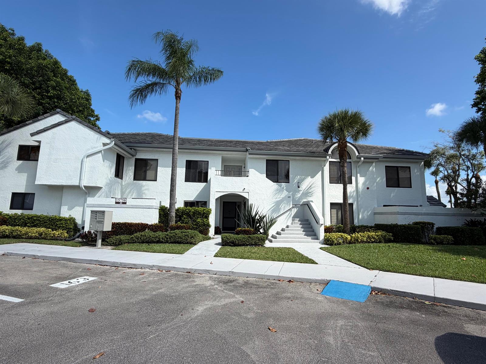 A two-story white stucco apartment building features a central staircase and two palm trees — 15758 Loch Maree Lane # 4005, Delray Beach FL 33446, DELRAY BEACH, FL