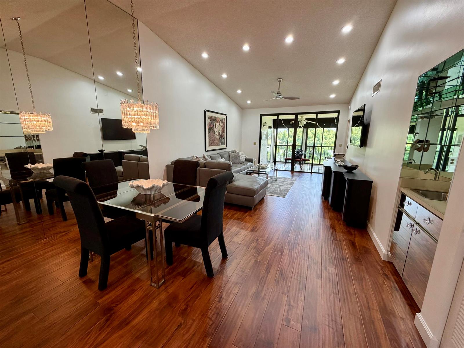 A dining area and living room feature wood flooring, mirrored walls, and a glass balcony door — 15758 Loch Maree Lane # 4005, Delray Beach FL 33446, DELRAY BEACH, FL