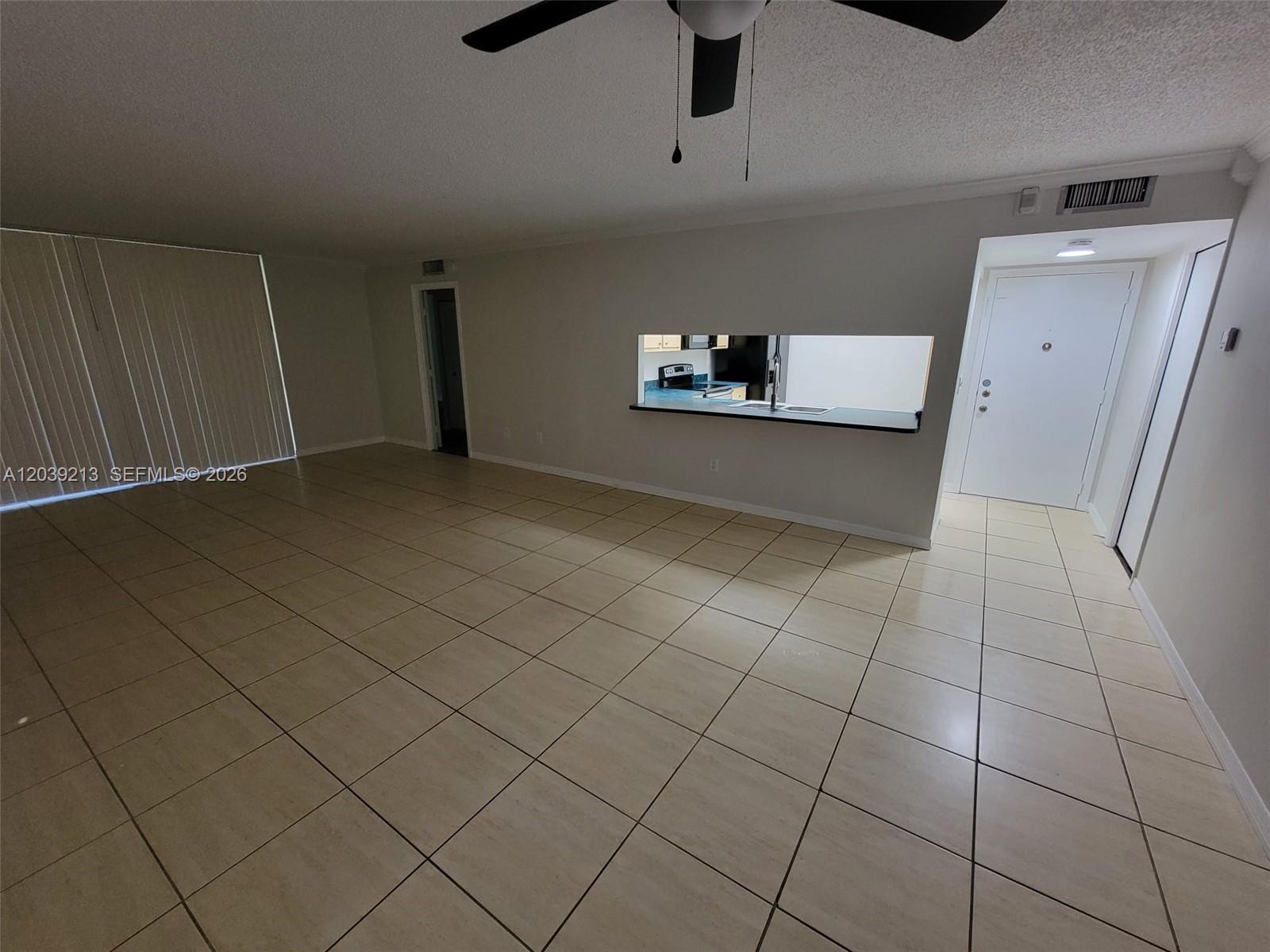 An open-concept living area features light-colored tile flooring, a ceiling fan, and a kitchen pass-through — PLANTATION, FL