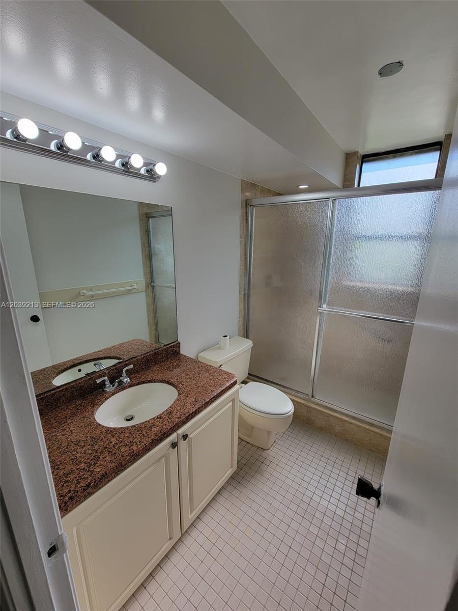 A bathroom features a granite vanity, a toilet, and a glass-enclosed shower — PLANTATION, FL
