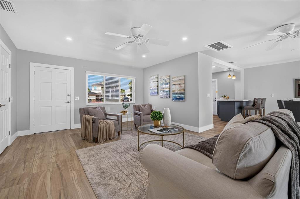 A living room features light gray walls, wood-look flooring, a beige sofa, and two armchairs — 8651 GULF BOULEVARD, ST PETE BEACH, FL