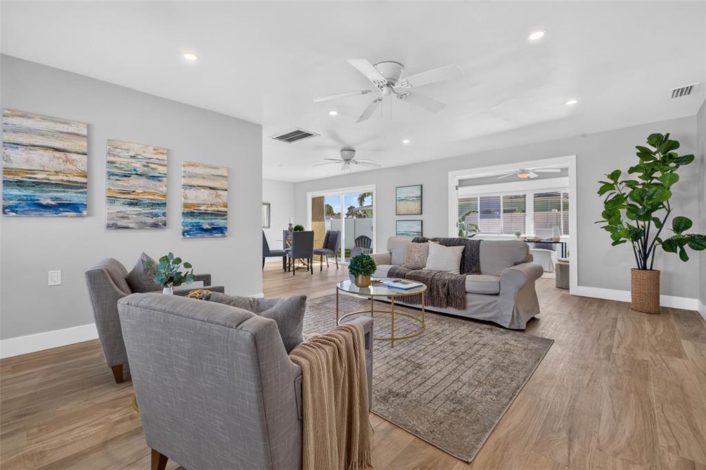A living room features gray furniture, a neutral rug, wood-look flooring, and a potted plant — 8651 GULF BOULEVARD, ST PETE BEACH, FL