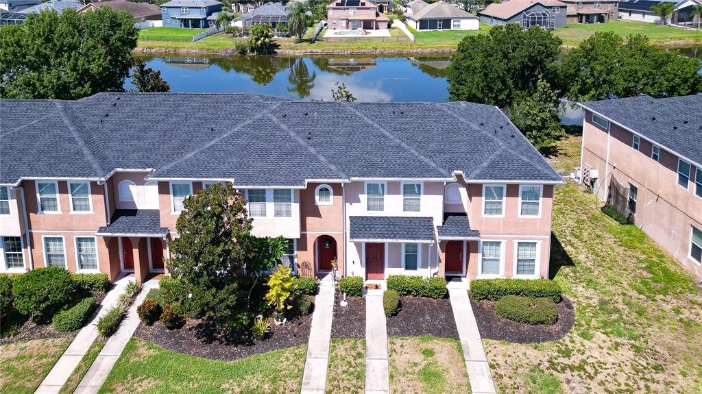 An aerial view shows a multi-unit townhouse complex with dark shingled roofs and landscaping — 6919 TOWERING SPRUCE DR, RIVERVIEW, FL