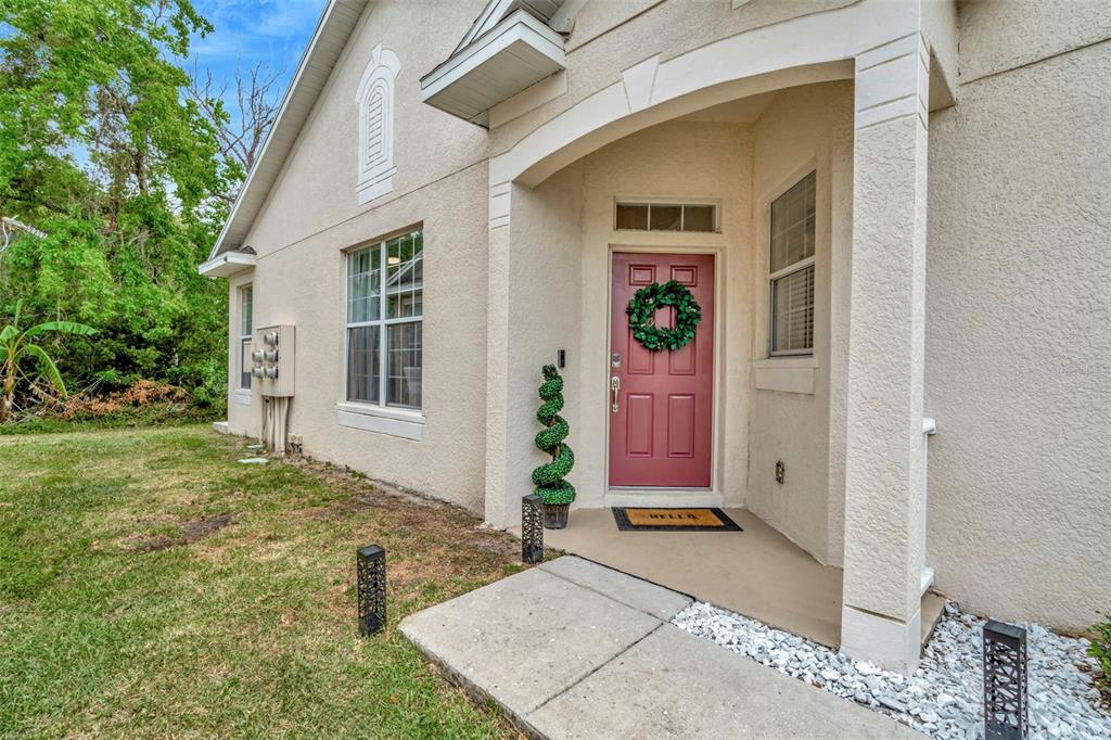 A beige stucco house exterior features a red front door with a green wreath — 6233 OLIVEDALE DRIVE, RIVERVIEW, FL