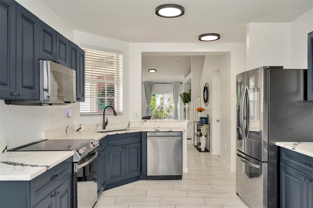 A kitchen with dark blue cabinets, white marble countertops, and stainless steel appliances — 6233 OLIVEDALE DRIVE, RIVERVIEW, FL