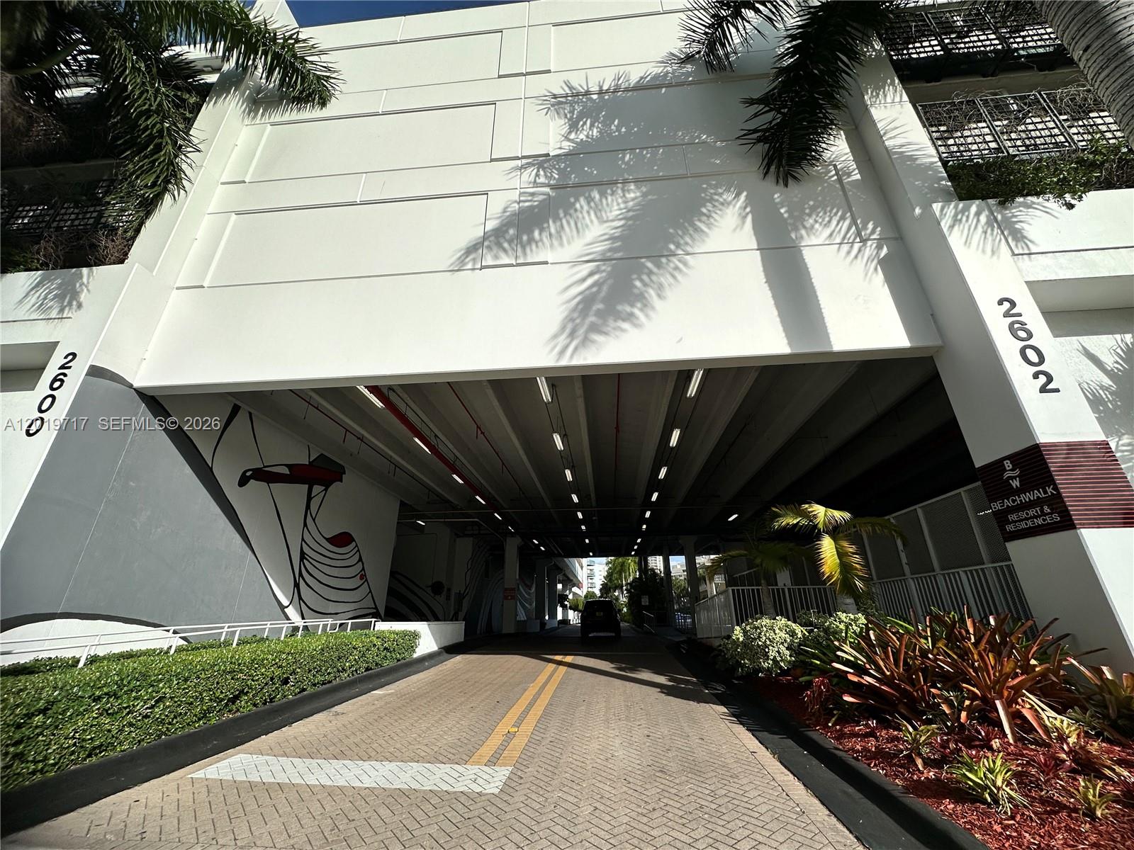 A paved driveway leads into the covered parking garage of a white multi-story building — 2602 E Hallandale Beach Blvd # R703, Hallandale Beach FL 33009, HALLANDALE BEACH, FL