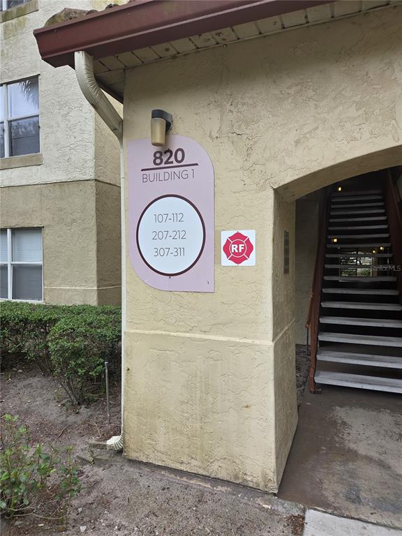 The exterior of a tan apartment building shows a sign indicating unit numbers for building 1 — 820 CAMARGO WAY UNIT 207, ALTAMONTE SPRINGS, FL