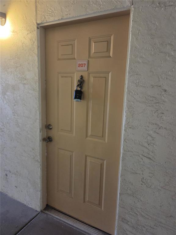 A beige apartment door with a lockbox hanging from a door knocker — 820 CAMARGO WAY UNIT 207, ALTAMONTE SPRINGS, FL