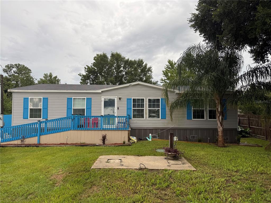 A single-story manufactured home with grey siding, blue shutters, and a wheelchair ramp — 3618 LATE MORNING CIRCLE, KISSIMMEE, FL