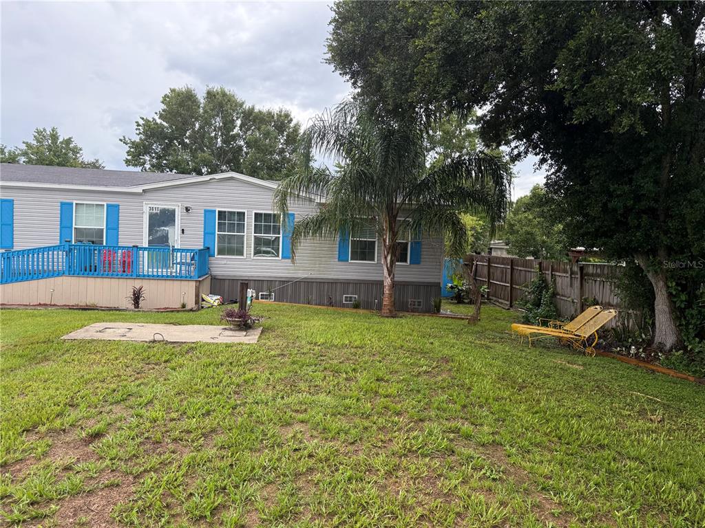 A manufactured home features a blue-railed ramp, a palm tree, and a yellow lounge chair — 3618 LATE MORNING CIRCLE, KISSIMMEE, FL