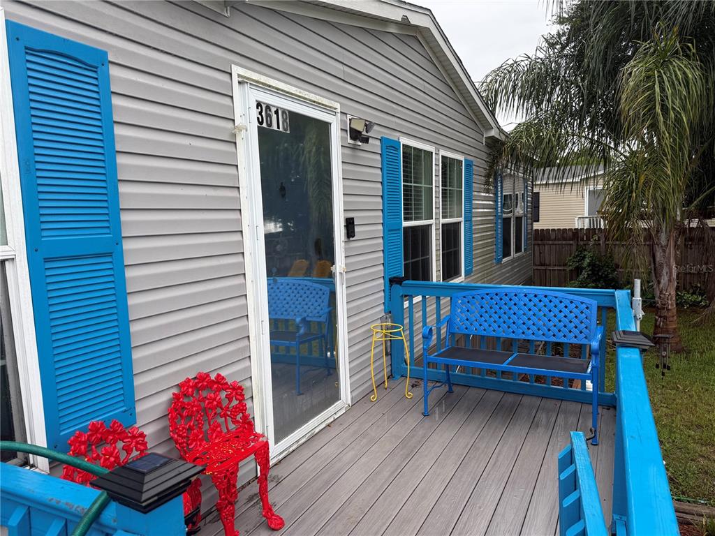A gray house exterior features a wooden deck with blue railings, a bench, and chairs — 3618 LATE MORNING CIRCLE, KISSIMMEE, FL