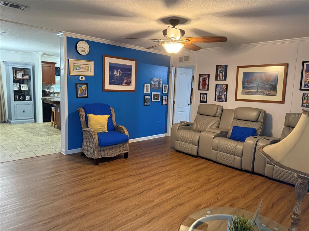 A living room features wood-look flooring, a blue accent wall, and a beige reclining sofa — 3618 LATE MORNING CIRCLE, KISSIMMEE, FL