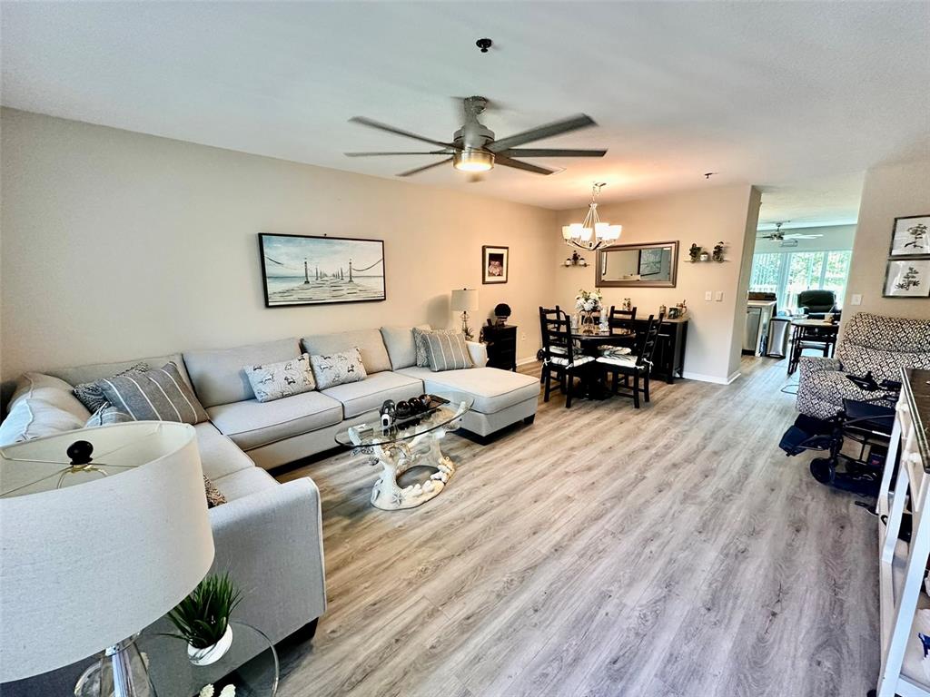 A living room and dining area feature light wood-look flooring, a sectional sofa, and furniture — 2020 SHANGRILA DRIVE UNIT 219, CLEARWATER, FL
