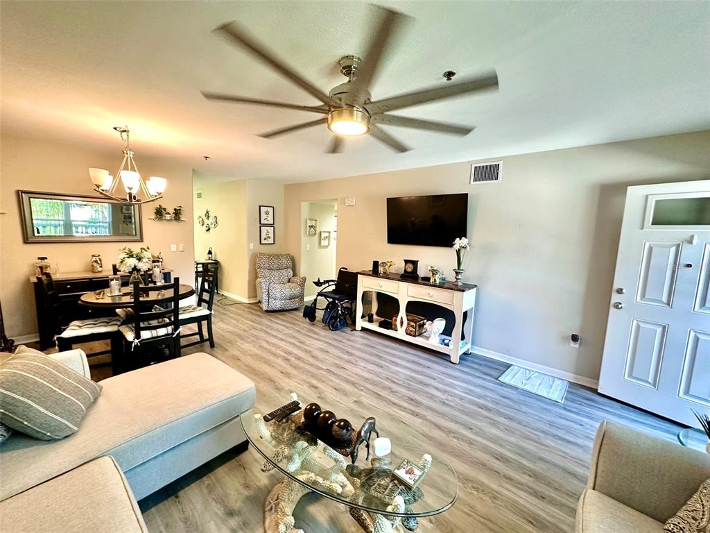 A living and dining area features light wood-look flooring, a ceiling fan, and neutral walls — 2020 SHANGRILA DRIVE UNIT 219, CLEARWATER, FL