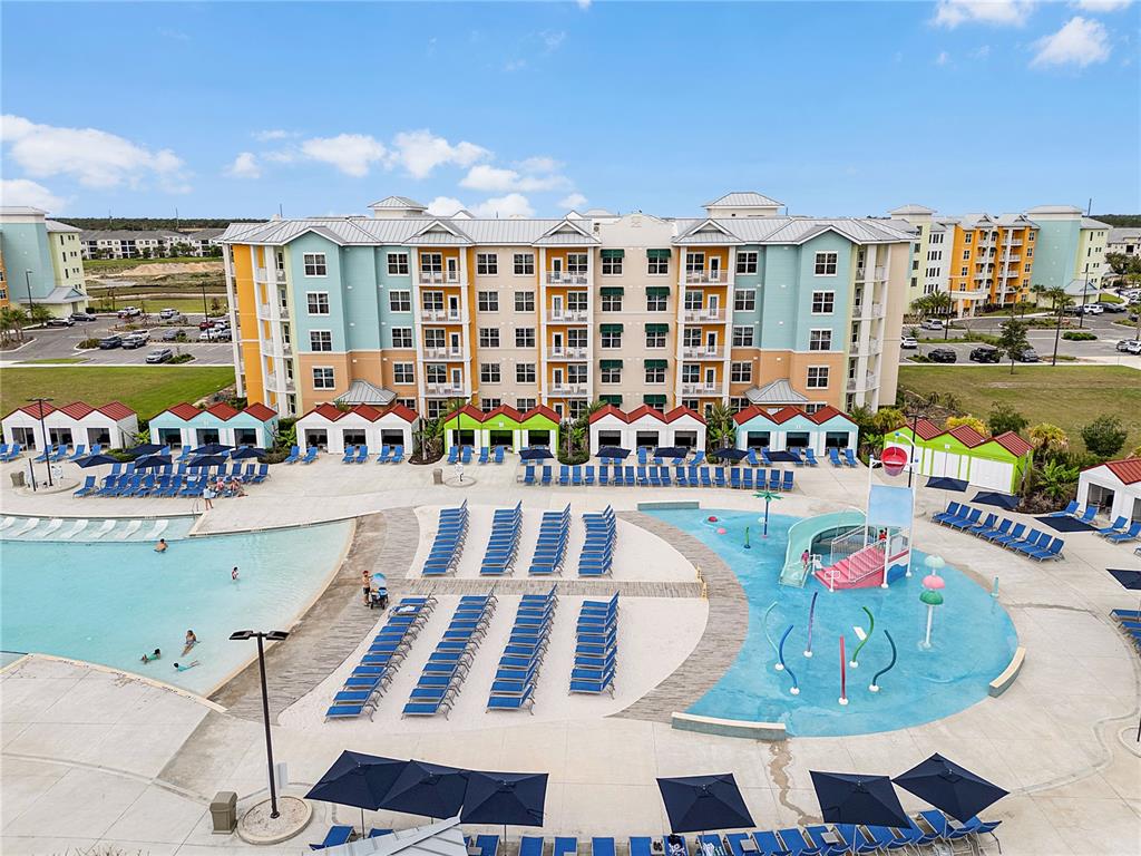 An aerial view shows a large apartment complex with a pool, splash pad, and cabanas — 8061 VACATION AVENUE UNIT 213, KISSIMMEE, FL