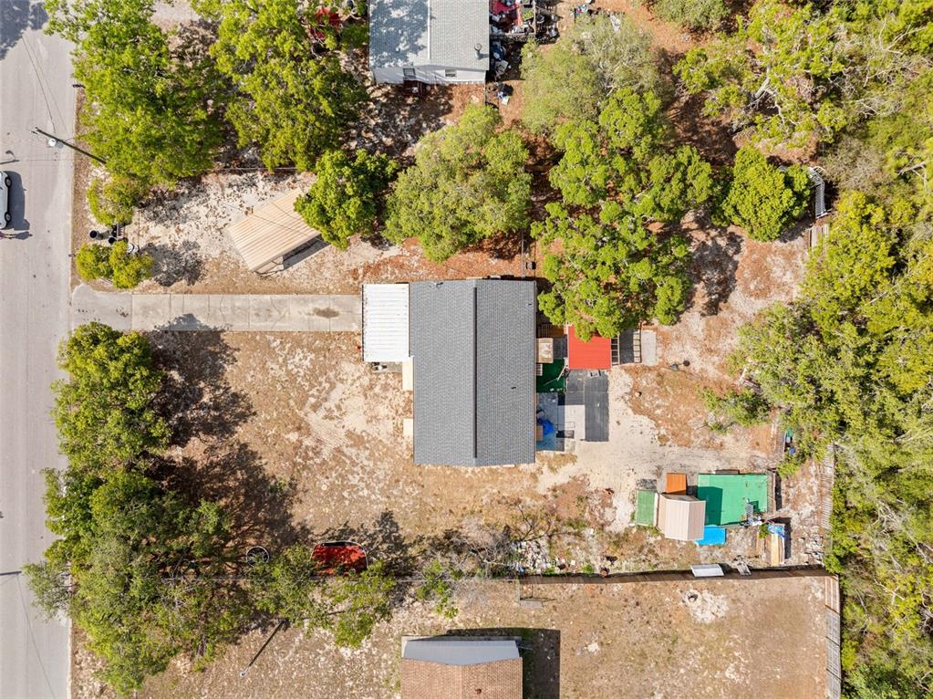 An aerial view shows a house with a gray roof, a driveway, and surrounding trees — 17322 HARMONY DRIVE, HUDSON, FL
