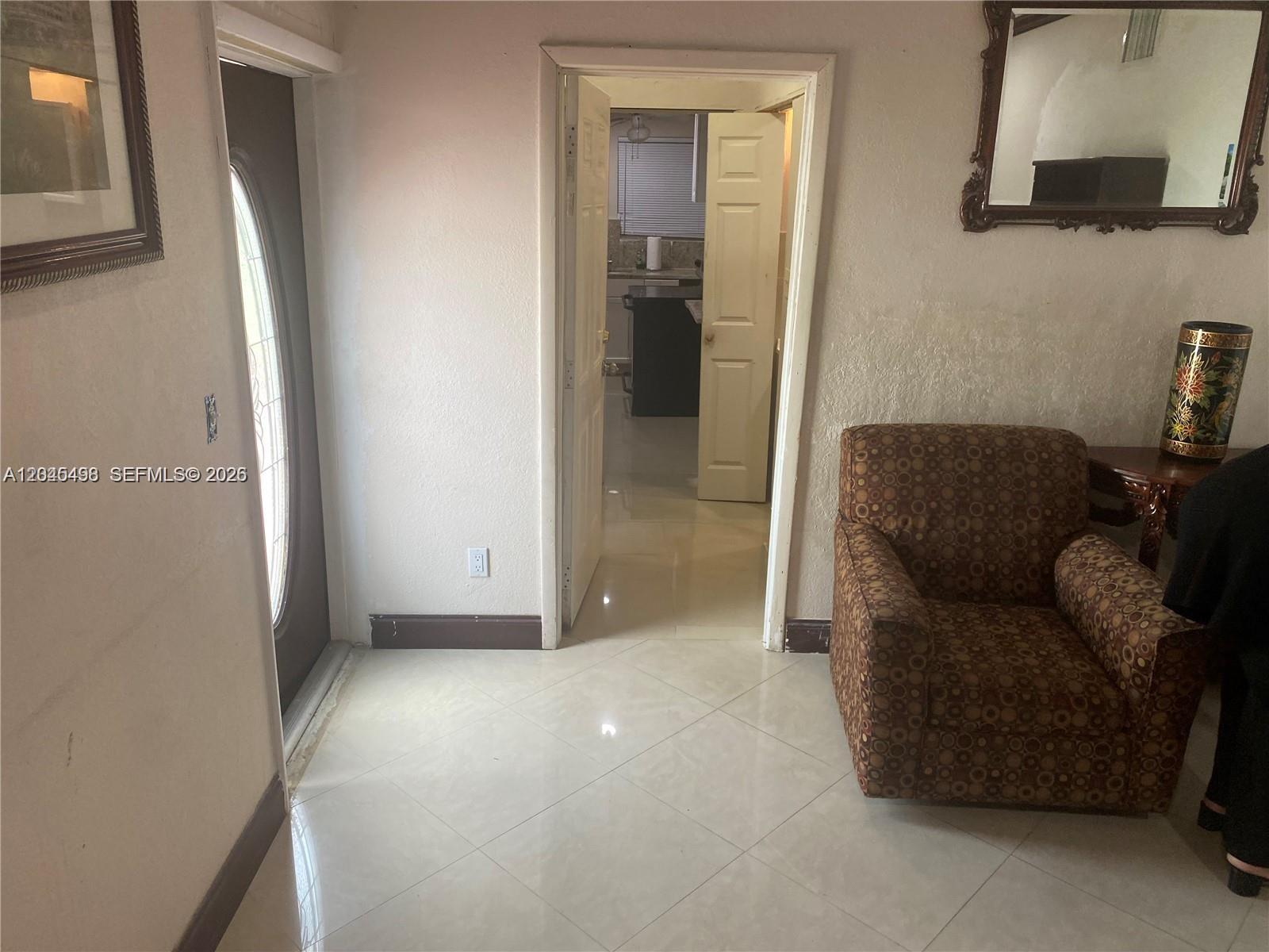 An entryway with tiled floors leads to a doorway revealing a kitchen area — MIRAMAR, FL