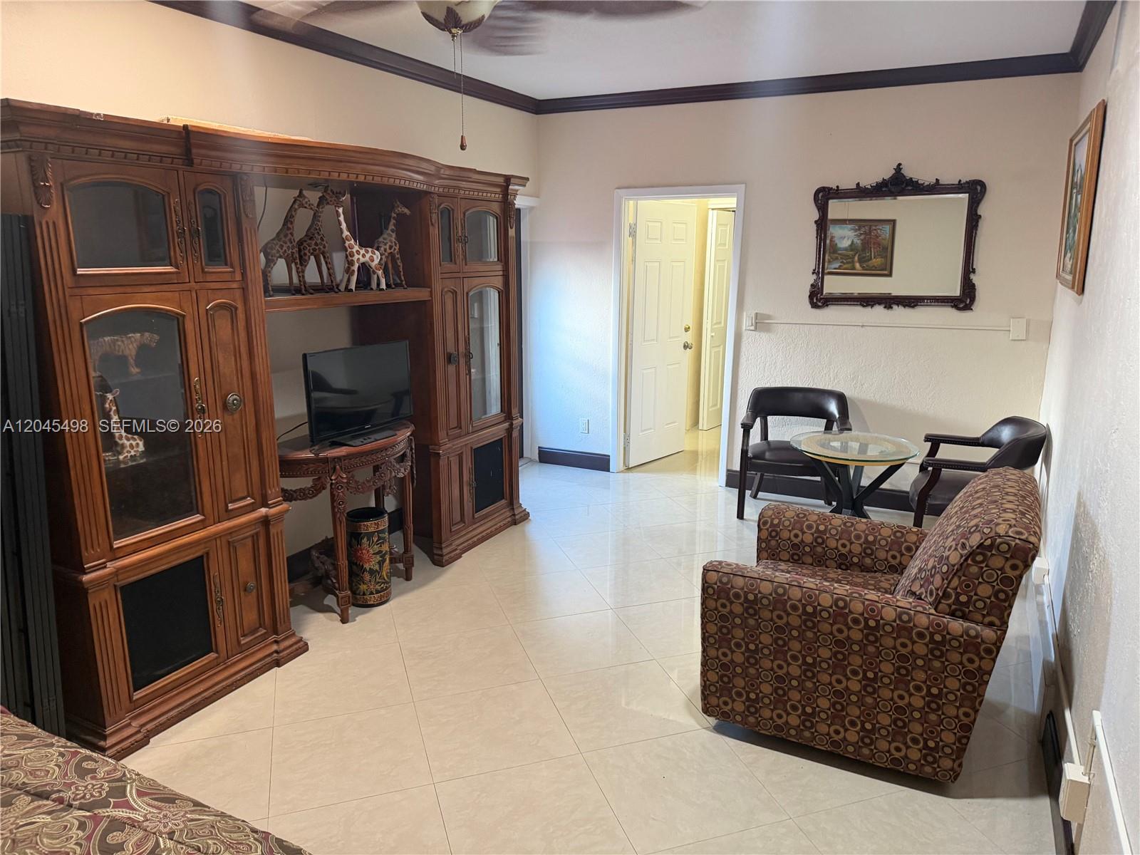 A living room features tile floors, a large wooden entertainment center, and patterned armchairs — MIRAMAR, FL