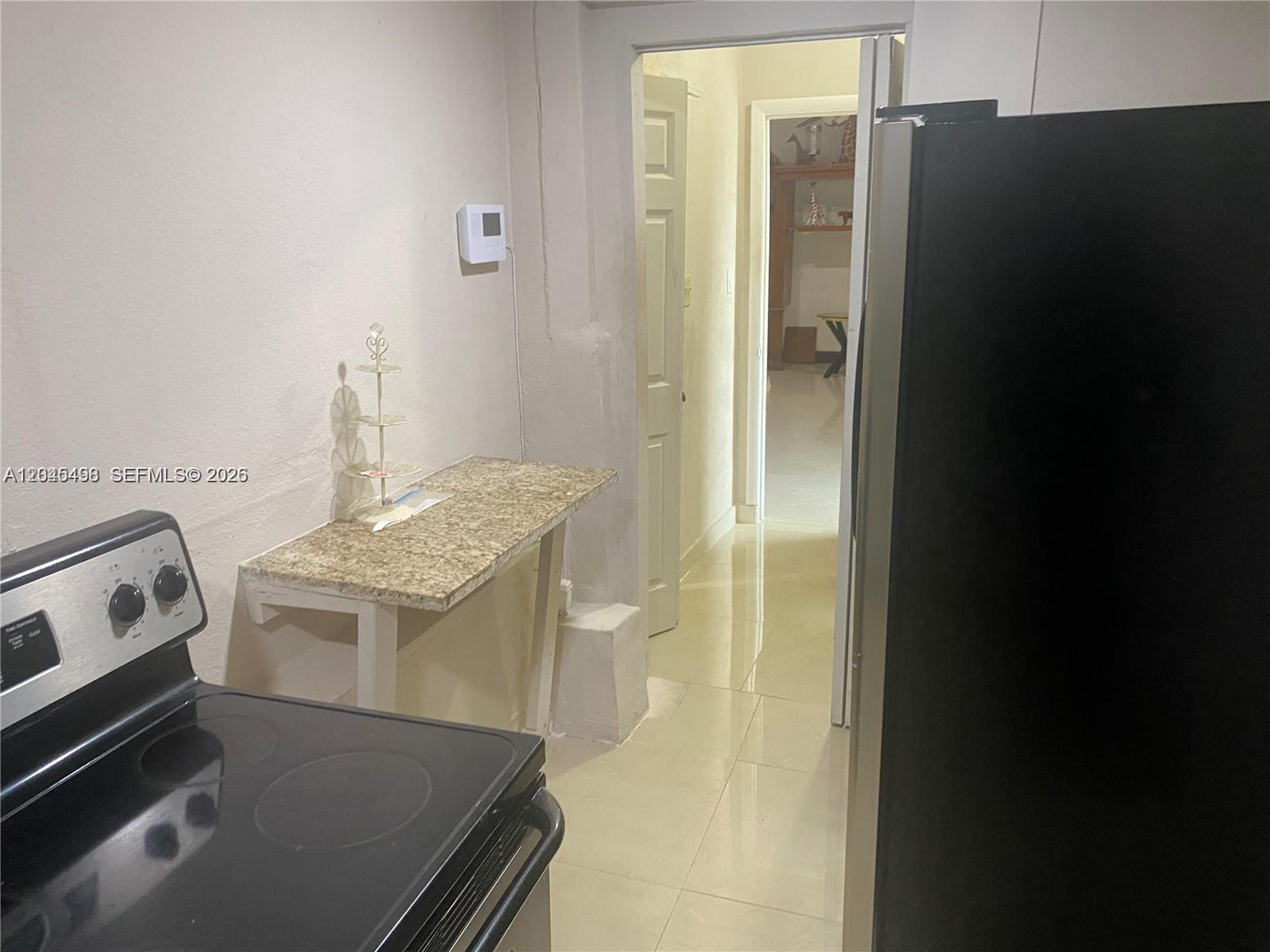A kitchen features a black stove, a granite-topped counter, and a doorway leading elsewhere — MIRAMAR, FL