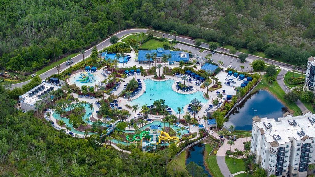 An aerial view shows a resort swimming pool complex with water slides and surrounding buildings — 14501 GROVE RESORT AVENUE UNIT 2635, WINTER GARDEN, FL