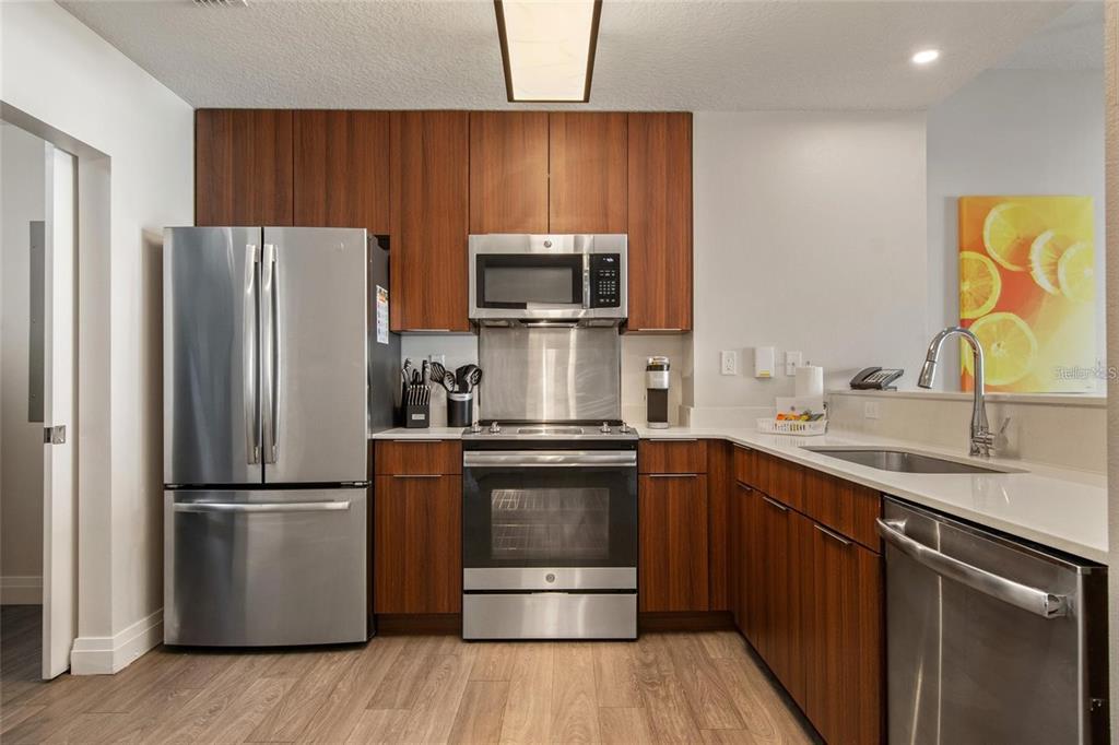 A modern kitchen features stainless steel appliances, wood-grain cabinets, and light-colored countertops — 14501 GROVE RESORT AVENUE UNIT 2635, WINTER GARDEN, FL
