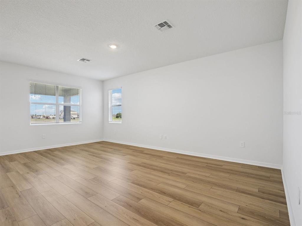 An empty room with white walls, light wood-look flooring, and two windows — 13220 SHELLMORE AVENUE, PALMETTO, FL
