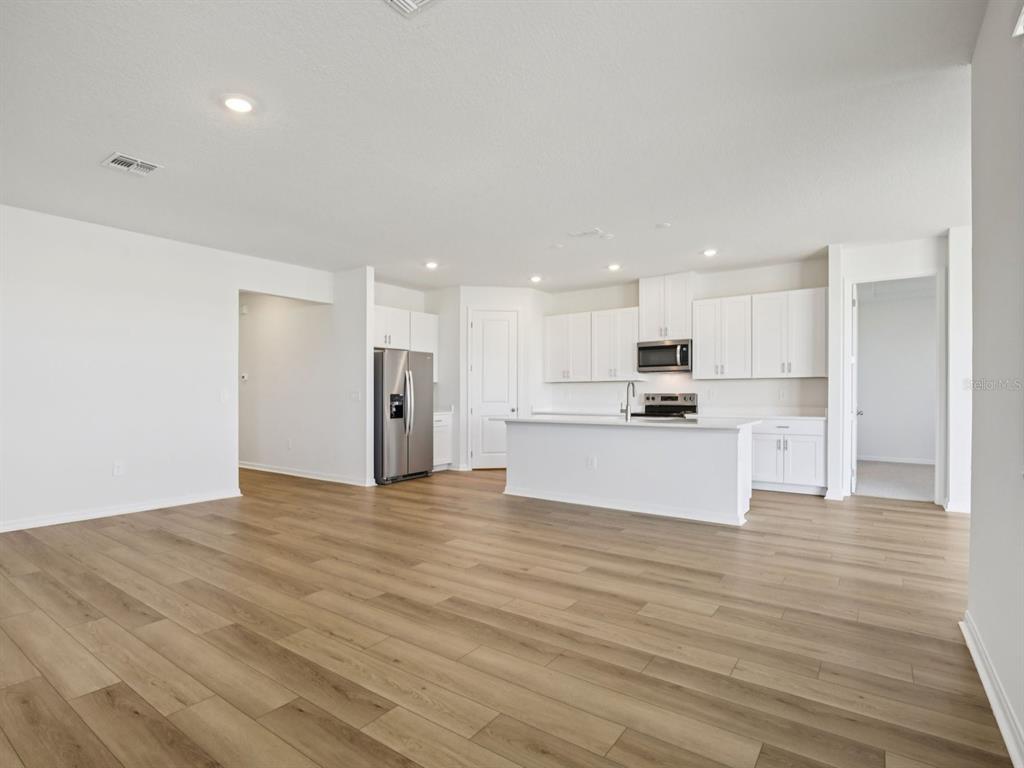 A kitchen with white cabinets, stainless steel appliances, and an island overlooks a living area — 13220 SHELLMORE AVENUE, PALMETTO, FL