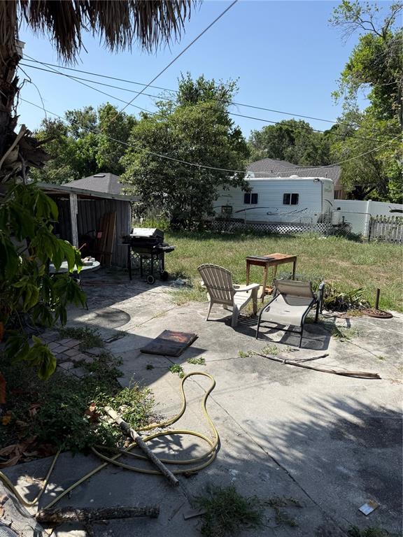 A backyard patio features a grill, outdoor furniture, a garden hose, and a parked trailer — 3012 N ALBANY AVENUE, TAMPA, FL