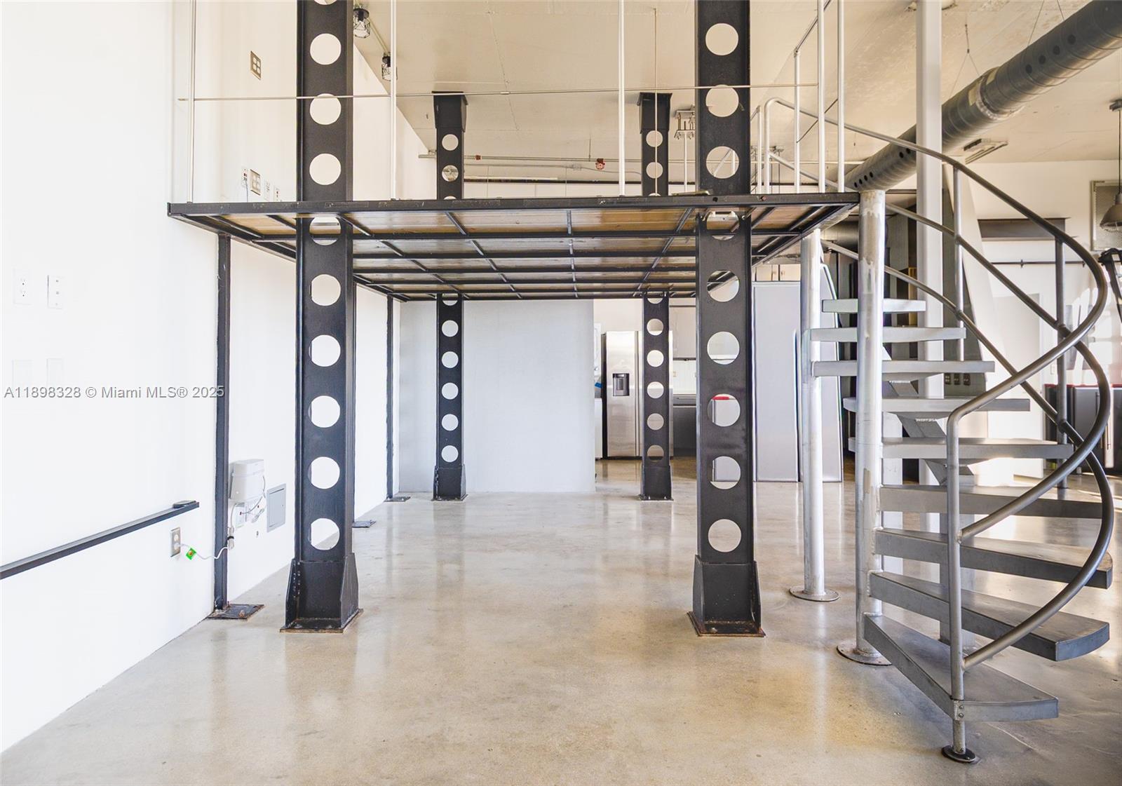 An industrial-style room features a metal mezzanine level supported by perforated steel beams and stairs — 250 NW 23 # 405, Miami FL 33127, MIAMI, FL