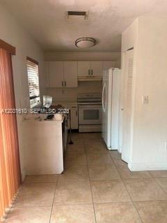 A kitchen with white cabinets, light-colored tile floors, and a white refrigerator — 9136 NW 192nd Ter, Hialeah FL 33018, HIALEAH, FL