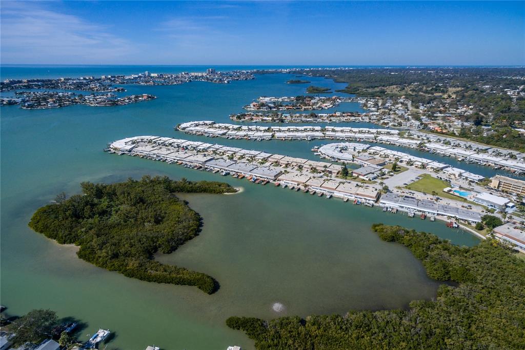 An aerial view shows a coastal residential community with boat slips and mangrove islands — 1 S BOCA CIEGA POINT BOULEVARD UNIT 204, ST PETERSBURG, FL