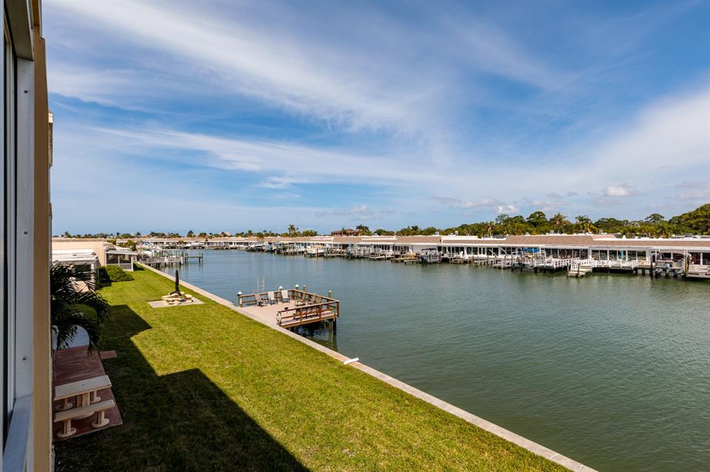 An elevated view of a grassy lawn, a wooden dock, and a canal with boats — 1 S BOCA CIEGA POINT BOULEVARD UNIT 204, ST PETERSBURG, FL
