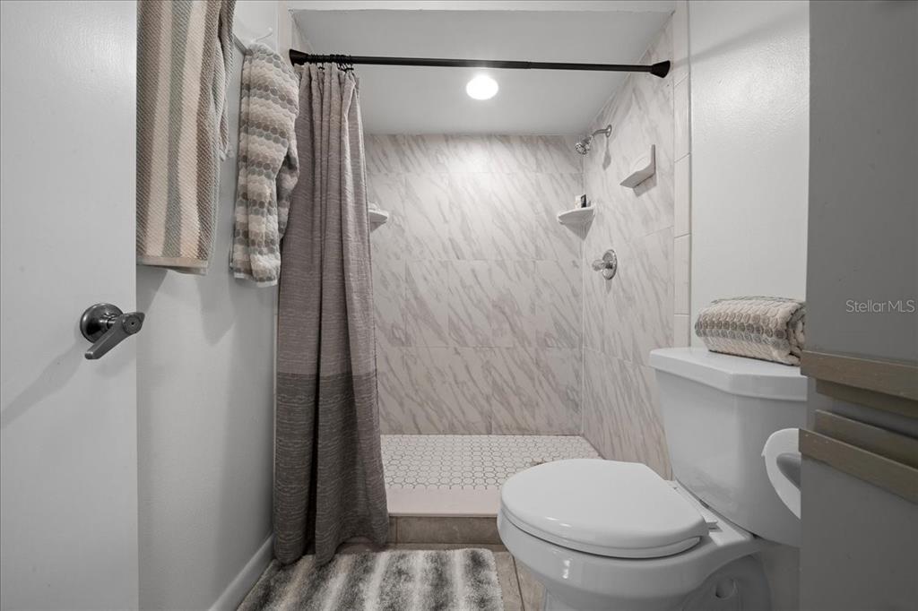 A bathroom features a walk-in shower with marble-look tile, a toilet, and gray accents — 2925 N RIVERS EDGE BOULEVARD UNIT 2925, CRYSTAL RIVER, FL