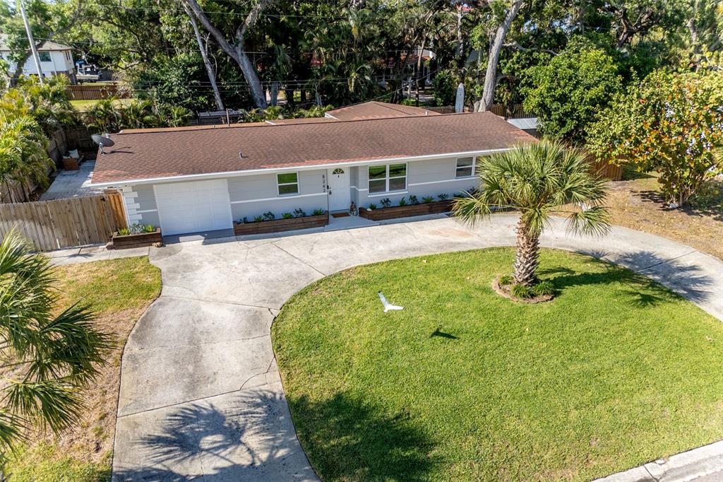 An aerial view of a single-story house with a driveway, front lawn, and palm tree — 8242 31ST TERRACE N, ST PETERSBURG, FL
