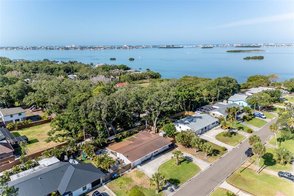 An aerial view shows a suburban neighborhood with houses, trees, and a large body of water — 8242 31ST TERRACE N, ST PETERSBURG, FL