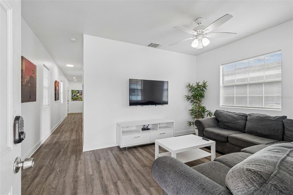 A living room features a gray sectional sofa, a white media console, and wood flooring — 1406 E 23RD AVENUE, TAMPA, FL