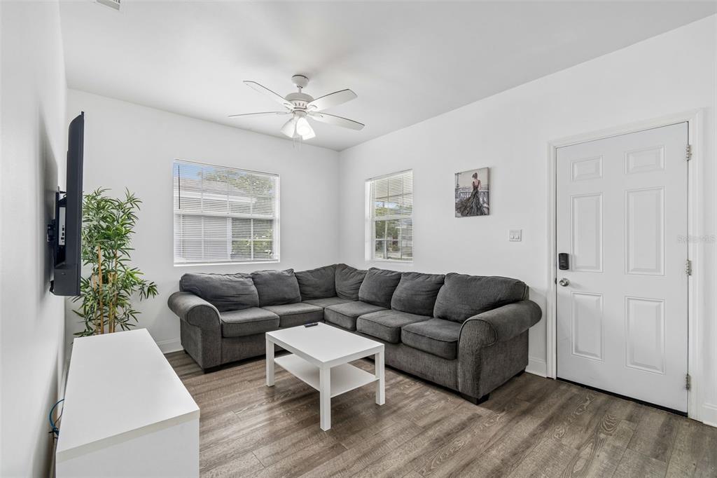 A living room features a gray sectional sofa, a white coffee table, and wood-look flooring — 1406 E 23RD AVENUE, TAMPA, FL
