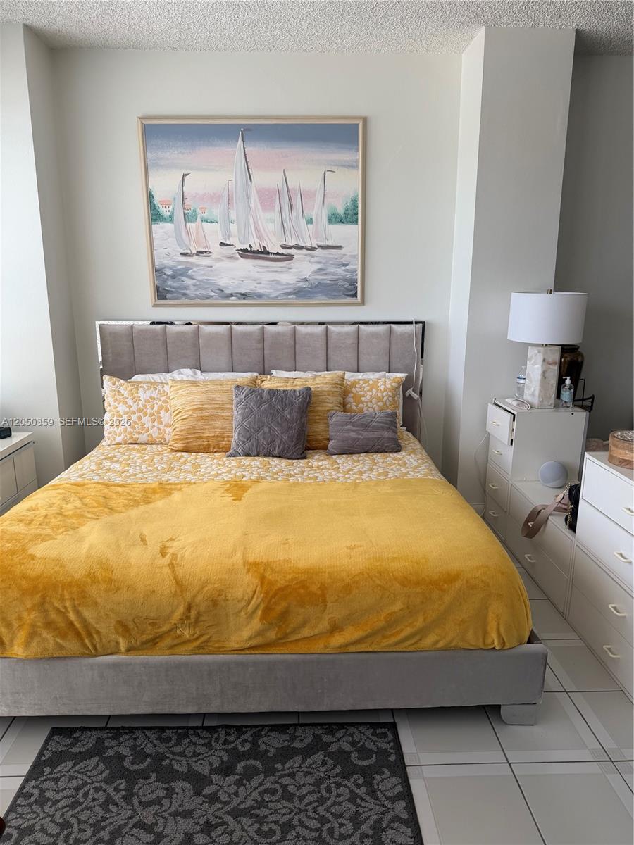 A bedroom features a bed with yellow bedding, a sailboat painting, and white furniture — 4925 Collins Ave # 2D, Miami Beach FL 33140, MIAMI BEACH, FL