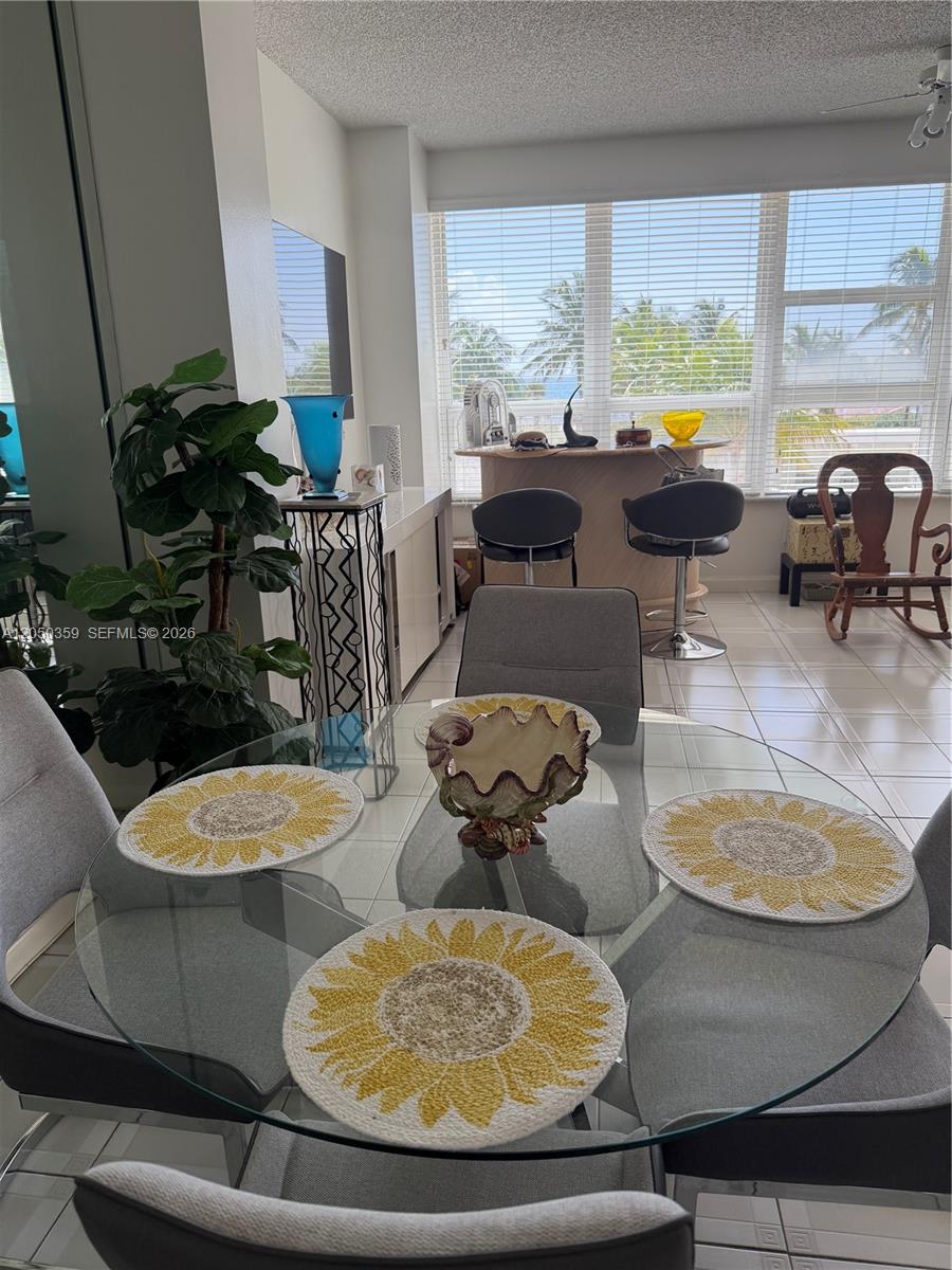 A dining area features a glass table with sunflower placemats and a nearby breakfast bar — 4925 Collins Ave # 2D, Miami Beach FL 33140, MIAMI BEACH, FL